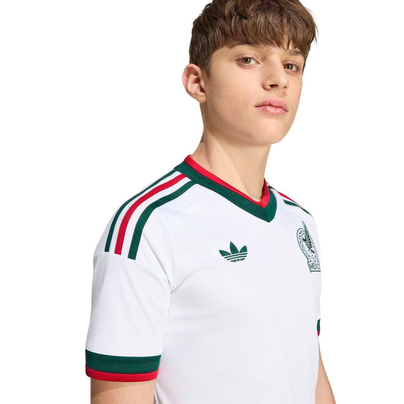 Youth white Mexico away jersey close-up showing green collar, stripes, and chest emblem