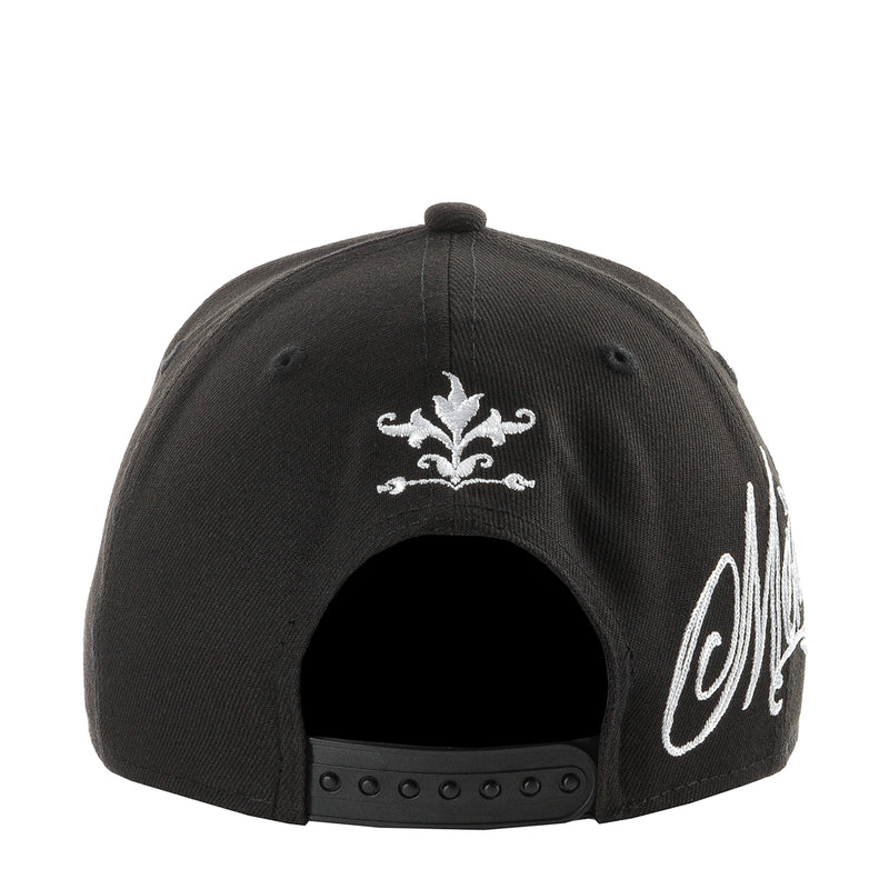 Black baseball cap with white fleur-de-lis and partial side script embroidery