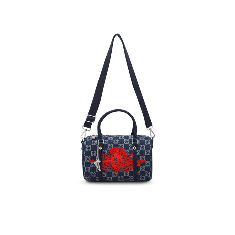 Dark indigo mini duffle bag with red emblem, zip top, and adjustable shoulder strap