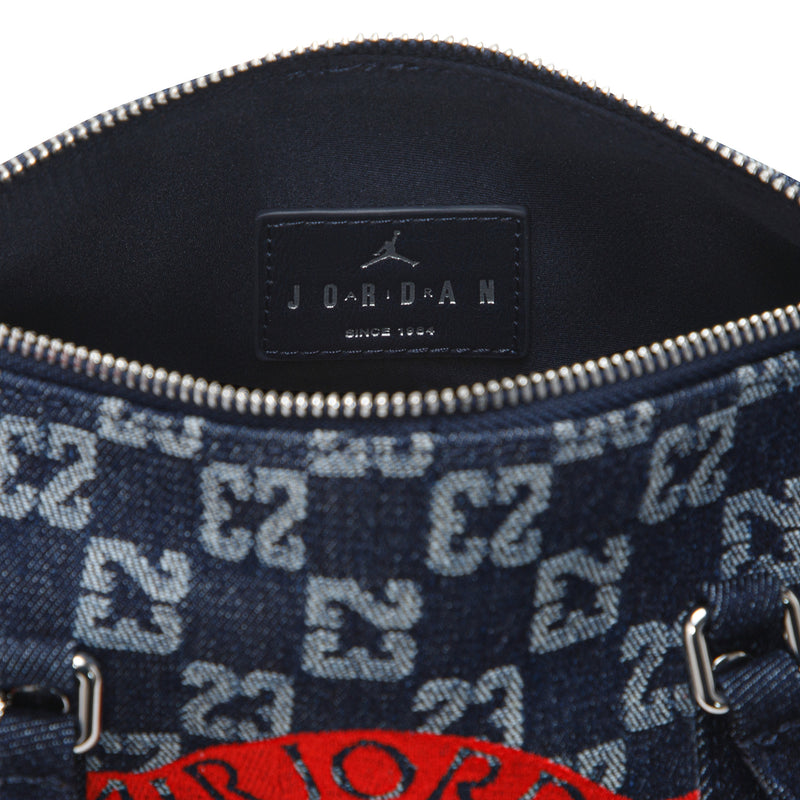 Close-up of dark indigo mini duffle bag interior pocket label and zipper trim