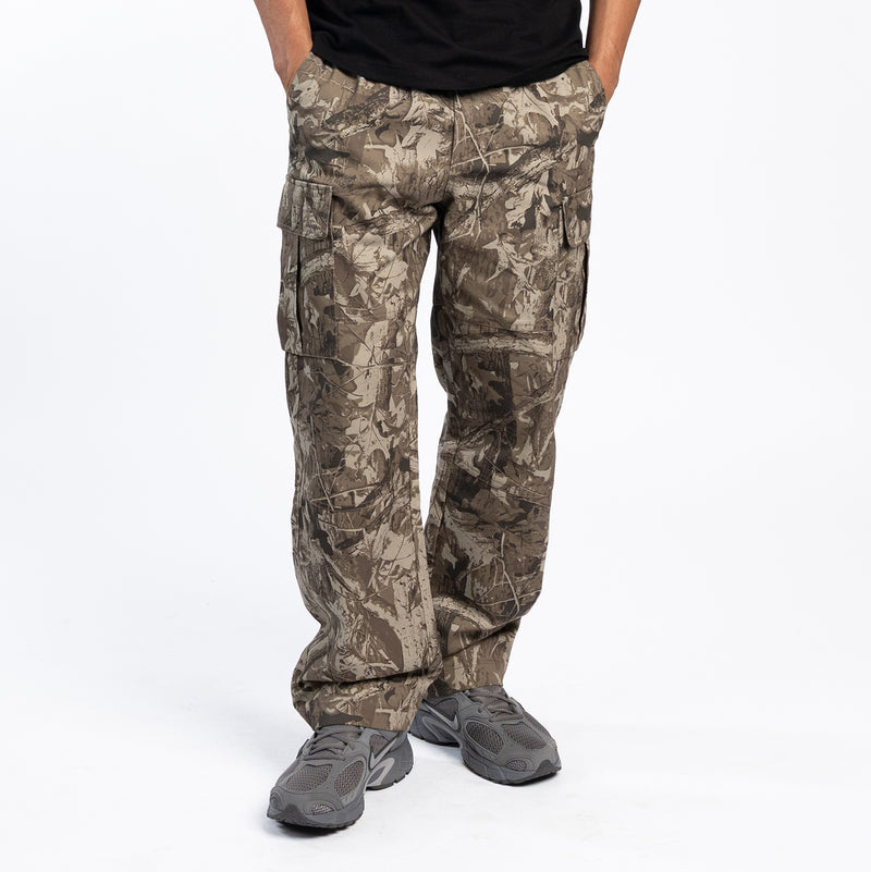 Tree camo cargo pants on model, side view with front pockets and tapered legs