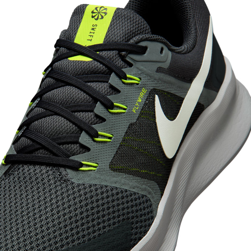 Close-up of men's black shoe upper with neon green laces and Flywire logo