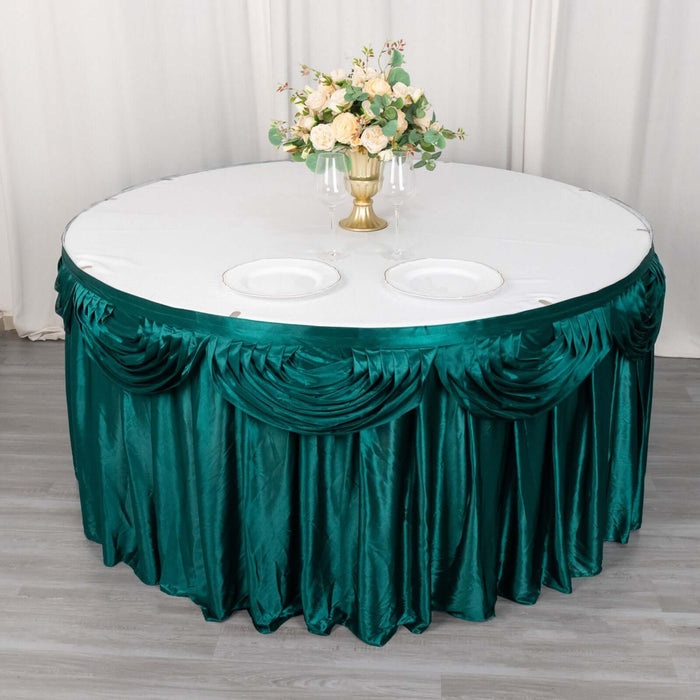 Round table draped with elegant green satin cloth and floral centerpiece.