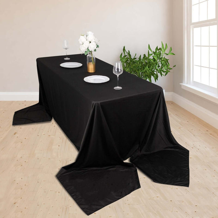 Elegant black tablecloth draped over a dining table set with plates and glasses.