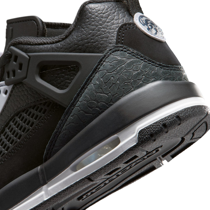 Close-up of youth black sneakers with textured side panel, white midsole, and black tread