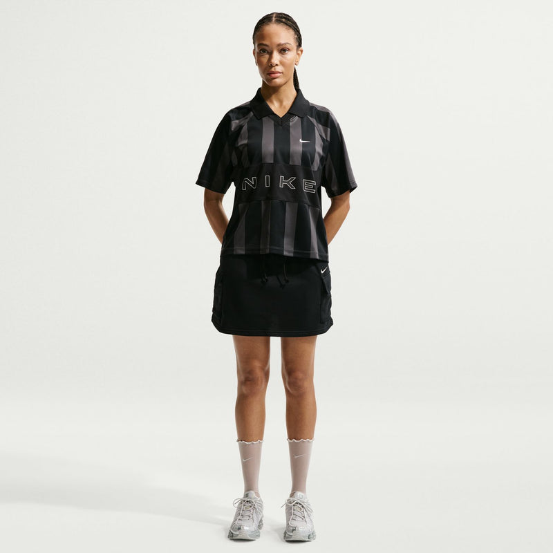 Women’s black striped jersey polo with pointed collar, Nike swoosh, and NIKE print