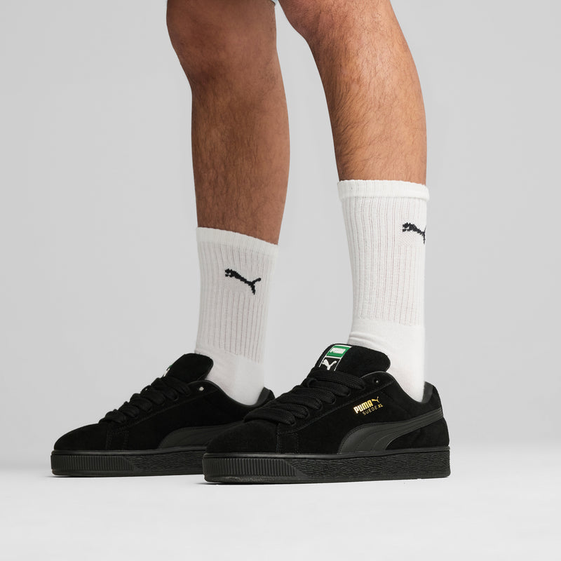 Black suede sneakers worn with white Puma socks and lace-up design