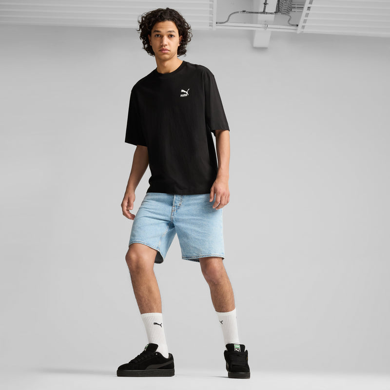 Black suede sneakers worn with light denim shorts and white Puma socks