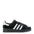 Women’s black patent leather sneaker with white three-stripe sidewall and black laces