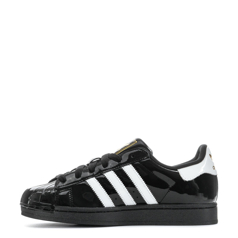 Women’s black patent leather low-top sneaker with white side stripes and lace-up closure