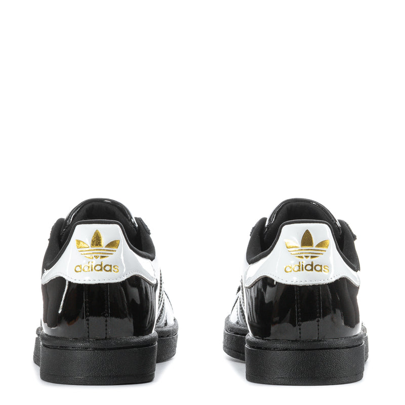 Women’s black patent leather sneakers from heel view with white adidas logo patch