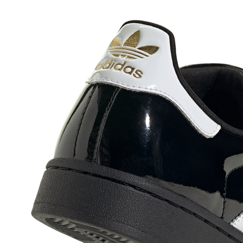 Women’s black and white patent leather sneaker with gold adidas logo on the heel tab