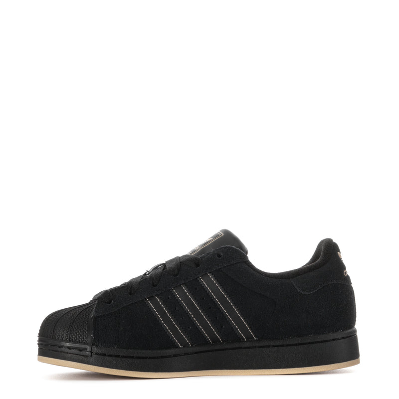 Youth black low-top sneakers, side view with three metallic stripes detail.