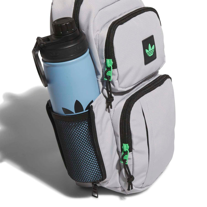 Light grey sling bag with black mesh side pocket holding a bottle; green cord accents