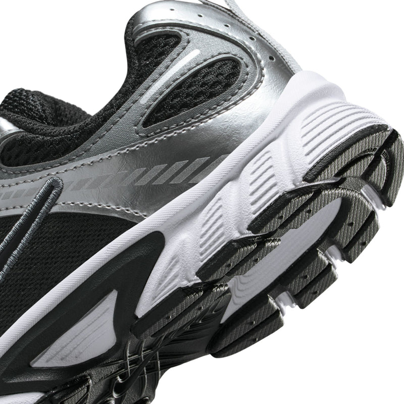 Kids sneaker close-up showing tread, black accents, and metallic silver upper.