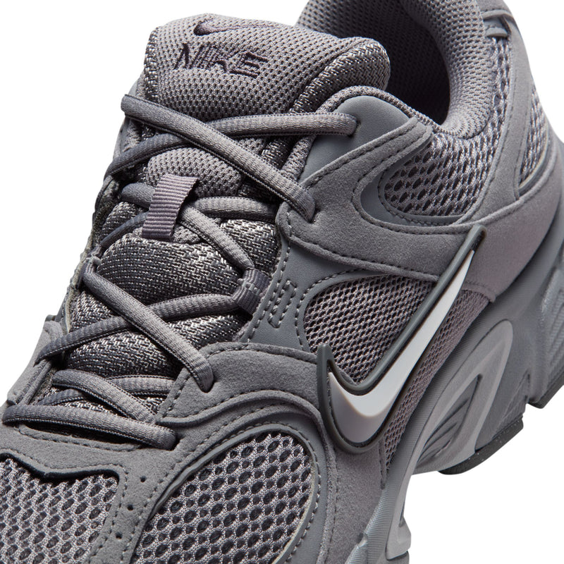 Close-up of grey lace-up running shoe with mesh texture, stitching, and Nike Swoosh.