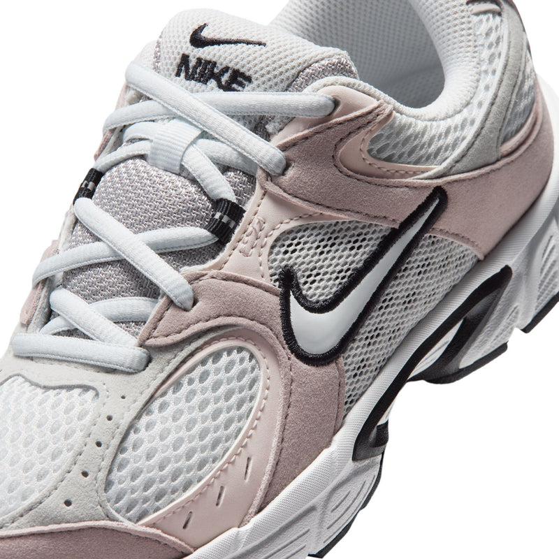 Close-up youth sneaker upper, white laces, mesh texture, pink suede, Nike swoosh.