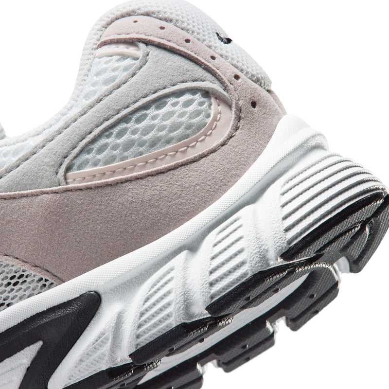 Close-up youth sneaker side, off-white sole grooves and pink suede with mesh panel.