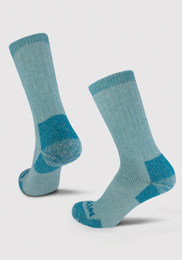 The Woolx Extreme Crew Socks in Real Teal are heavyweight socks designed for ultimate warmth during colder days. These light blue Merino wool socks feature darker blue reinforced heels, toes, and cuff edges. They stand upright with one slightly in front of the other, showcasing both the top and bottom designs.